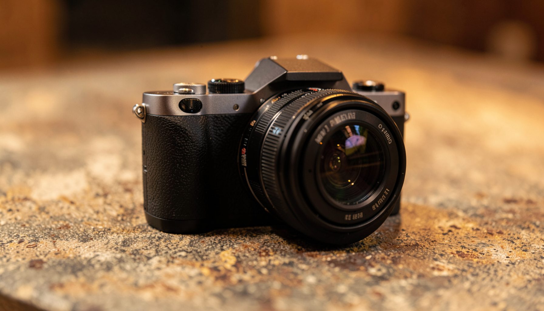 A sleek camera body with a compact form factor, resting on a textured surface in warm ambient light